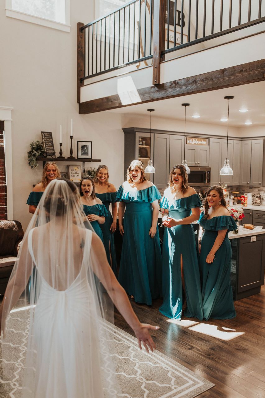 Bride revealing her dress to her bridal party in the house at Three Strands Farm